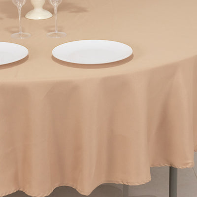 Beige tablecloth draped over a round table with two white plates.