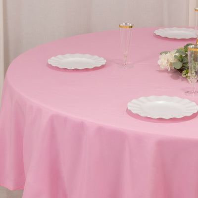 Pink tablecloth with white plates and elegant glassware set for dining.