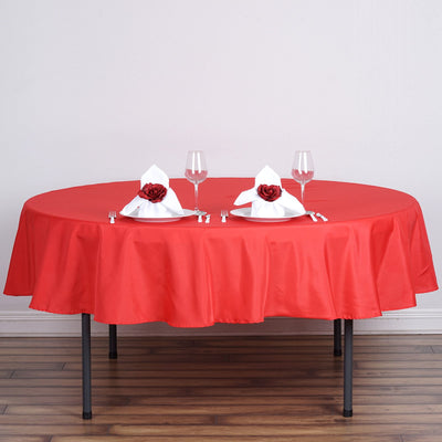 Elegant red tablecloth set for dining with white napkins and roses.