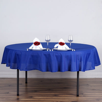 Round blue tablecloth with elegant napkin presentation and glasses.