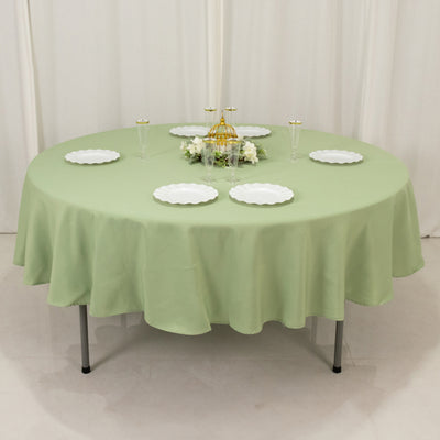 Round green tablecloth with white plates and decorative centerpiece.