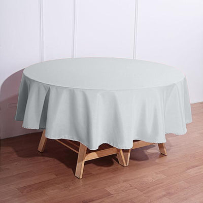 Round light gray tablecloth draped over a wooden table.