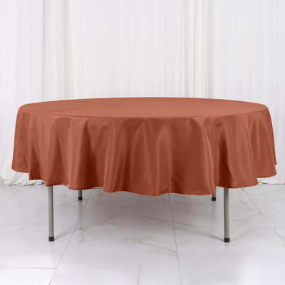Round tablecloth in terracotta color on a round table.
