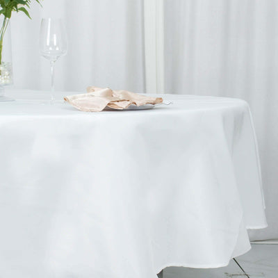 Elegant white tablecloth draping a round table with a plate and glass.