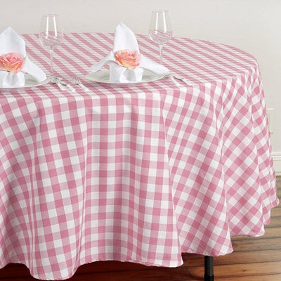 Pink and white gingham tablecloth set for dining with glasses and napkins.