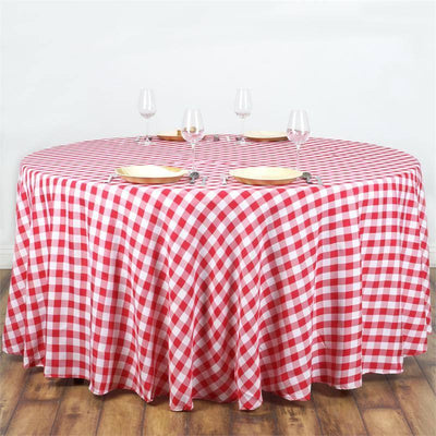 Round red and white checkered tablecloth on a dining table with plates and glasses.