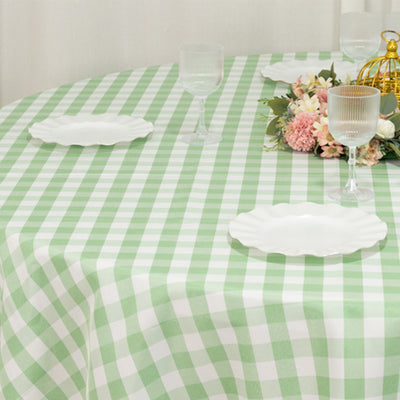 Green gingham tablecloth on a round table with plates and floral arrangement.