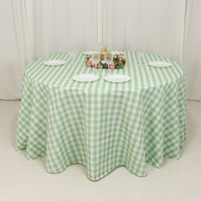 Green gingham tablecloth on a round table with decorative plates and flowers.