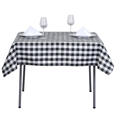 Black and white checkered tablecloth with two glasses and napkins on a table.