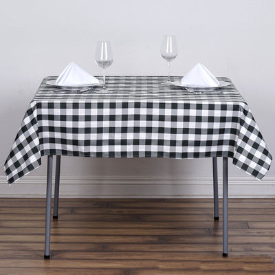 Black and white checkered tablecloth on a dining table with glasses and napkins.