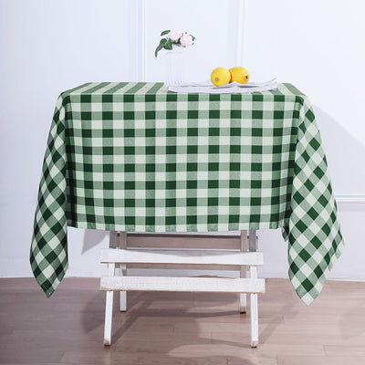 Green and white checkered tablecloth on a wooden table with lemons and flowers.