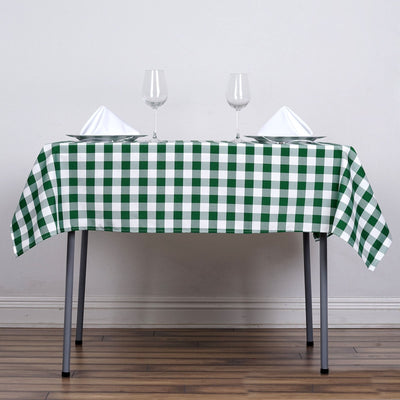 Green and white checkered tablecloth on a dining table with glasses and napkins.