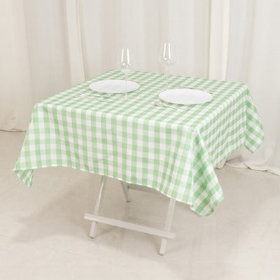 Green and white checkered tablecloth on a folding table with plates and glasses.