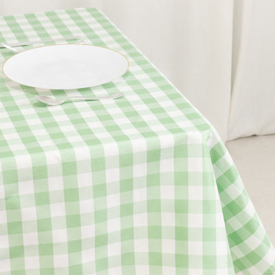 Green gingham tablecloth on a dining table with a white plate and cutlery.