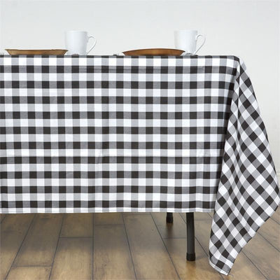 Black and white checkered tablecloth draping over a table with dishes and cups.
