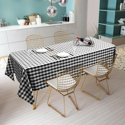 Black and white checkered tablecloth on a dining table with gold wire chairs.