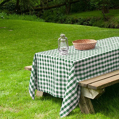 Picnic table with green and white checkered tablecloth, glass jar, and woven basket.