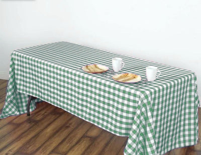 Green and white checkered tablecloth on a wooden table with plates and cups.