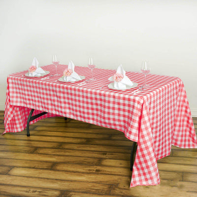 Red and white checkered tablecloth draped over a dining table with napkins and glasses.