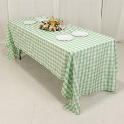 Green gingham tablecloth on a dining table with floral centerpiece and plates.