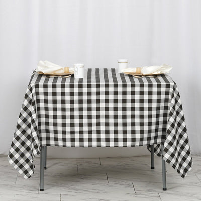 Black and white checkered tablecloth on a dining table with napkins and cups.