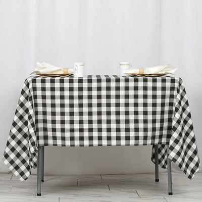 Black and white checkered tablecloth on a table with napkins and cups.