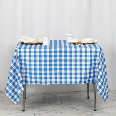 Blue and white gingham tablecloth on a table with cups and napkins.