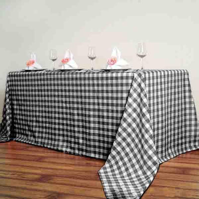 Black and white checkered tablecloth draped over a table with glasses and napkins.