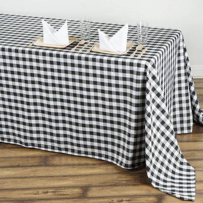 Black and white checked tablecloth on a wooden table with dinner settings.