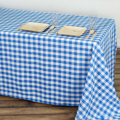 Blue and white checkered tablecloth on a wooden table with plates and glasses.