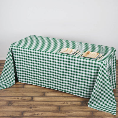 Green and white checkered tablecloth on wooden floor with plates and glasses.