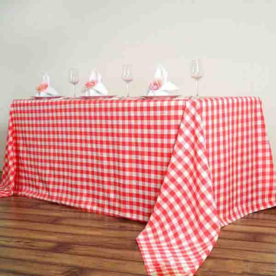 Red and white checkered tablecloth draped on a wooden table with glasses and napkins.