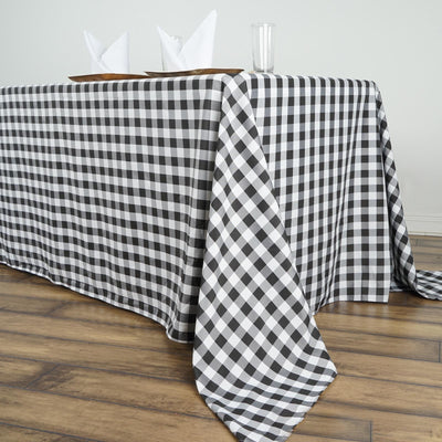 Black and white checkered tablecloth draped over a table with napkins and glass.