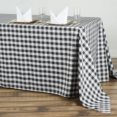 Black and white checkered tablecloth on a wooden table with napkins and glasses.