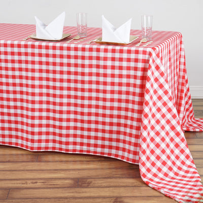 Red and white checkered tablecloth on a wooden table with napkins and glasses.