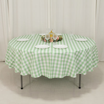 Green checkered tablecloth on an elegant round table setting with plates.