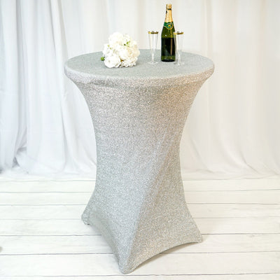 Silver glitter table cover with champagne bottle and glasses on a festive backdrop.