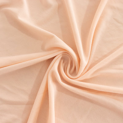 Peach fabric with a soft, smooth texture arranged in a spiral pattern.