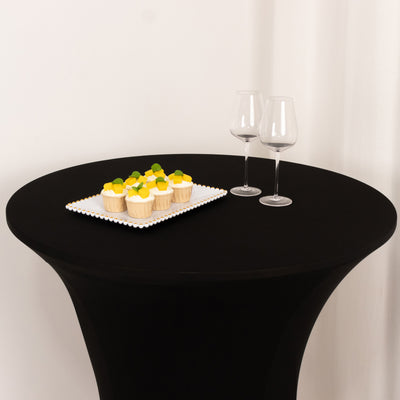 Cupcakes on a tray with wine glasses on a black table.