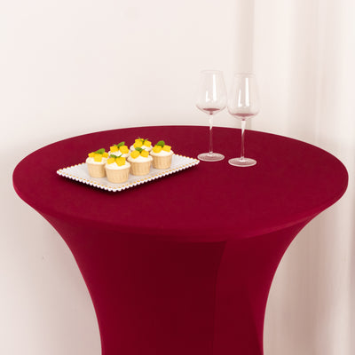 Round table with cupcakes and wine glasses on a burgundy tablecloth.