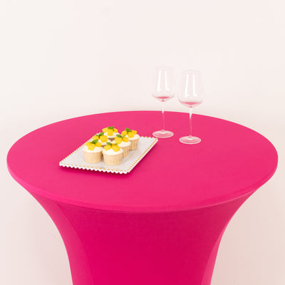 Pink table with cupcakes and two wine glasses on a white background.
