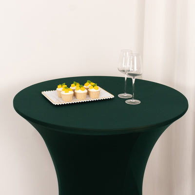 Green table with cupcakes and wine glasses on a white backdrop.