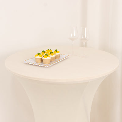 Cupcakes on a platter with two wine glasses on a round table.