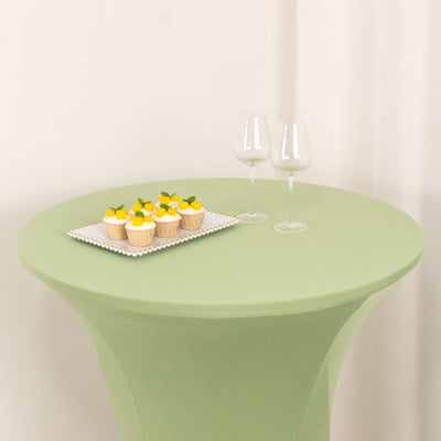 Green table with cupcakes and two wine glasses on a white backdrop.