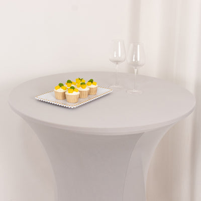 Table with cupcakes and two wine glasses on a plain background.
