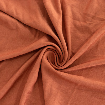 Textured rust-colored fabric in a circular swirl pattern.