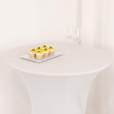 Cupcakes on a tray beside two glasses on a round white table.