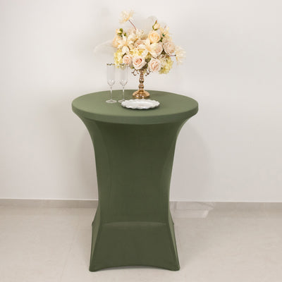 Round green cocktail table with floral centerpiece and glasses.