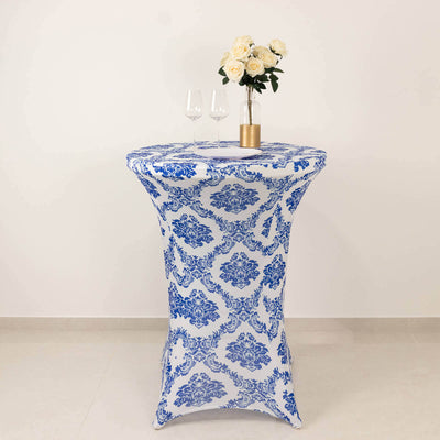 Blue and white patterned table cover with a vase of roses and glasses on a tall table.