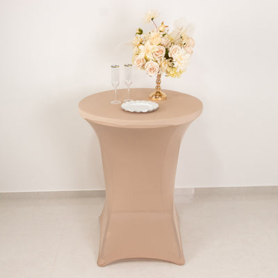 Elegant round table with beige cover, adorned with flowers and glassware.
